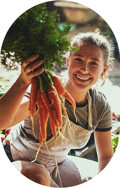 Usměvavá farmářka s čerstvě sklizenou mrkví ze sezónní úrody